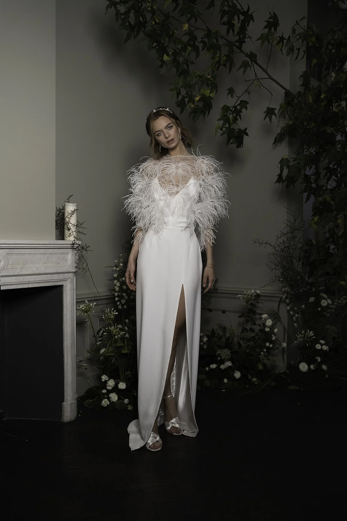 Womand wearing a white bridal slip dress with tulle shirt adorned with ostrich feathers