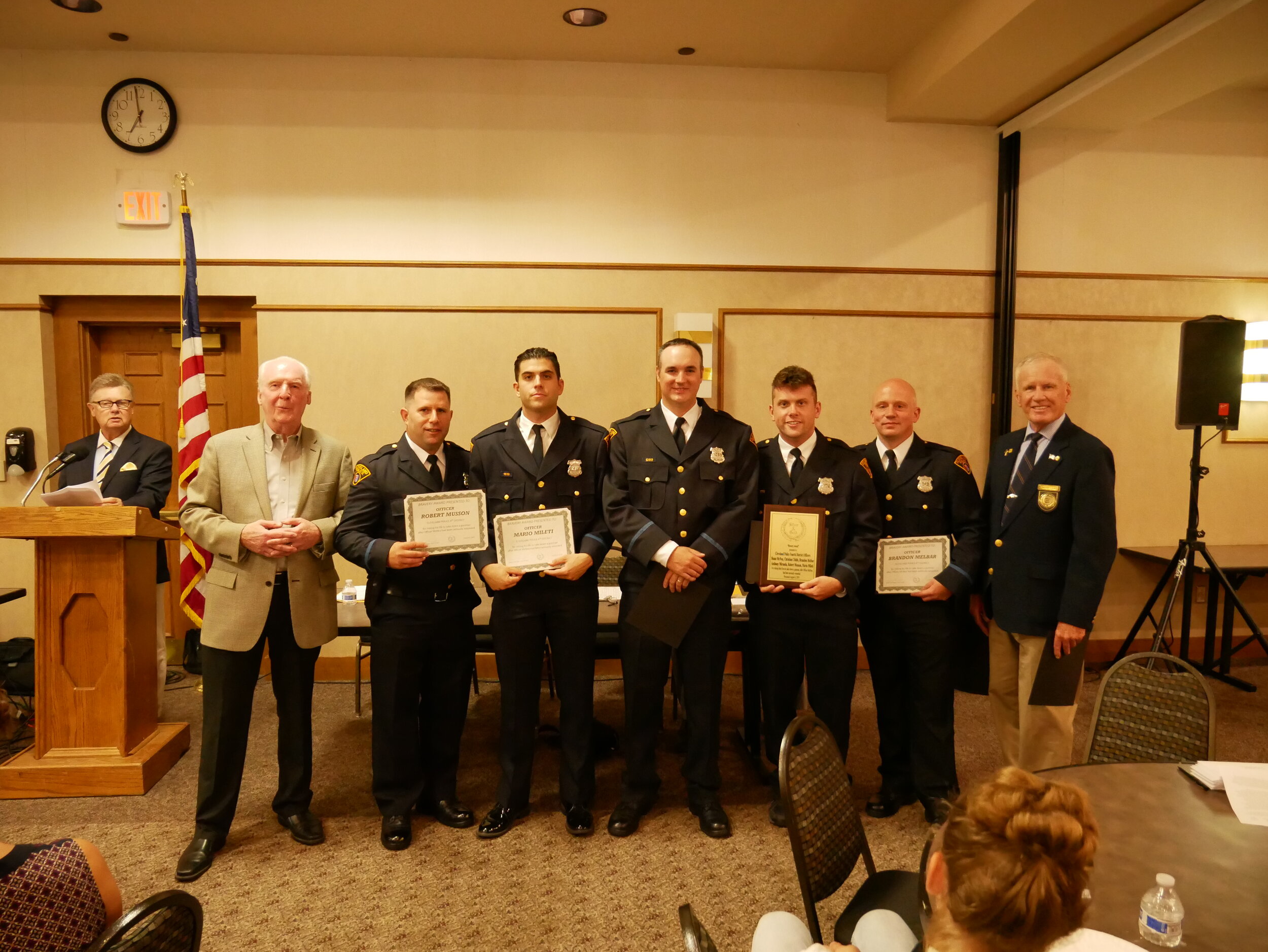  Board Member Mike Dugan at the microphone, Board Member Pat Reynolds with President Tim Leahy on the right presenting a Bravery Award to Officers Robert Musson, Mario Milati, Christopher Childs, Steve McNea, Anthony Miranda, and Brandon Melbar for r