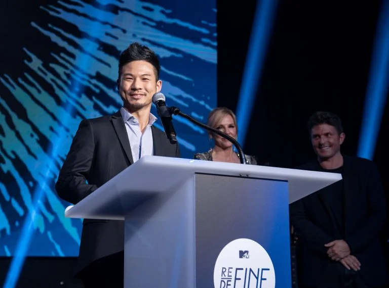 Shohei Katayama (Carnegie Mellon University), winner of the inaugural MTV RE:DEFINE Award in 2019, accepts his award as Joyce Goss and Kenny Goss look on.
