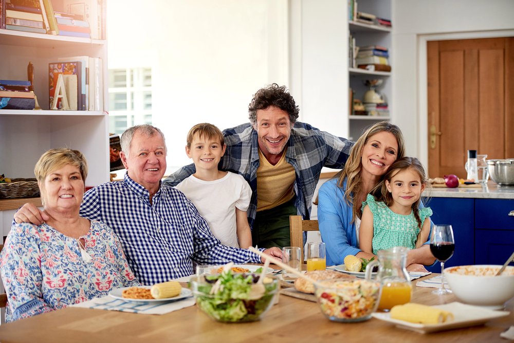 Multi-generational family gathered around a dining table, illustrating how changing family needs can influence renovation priorities and home modification decisions.