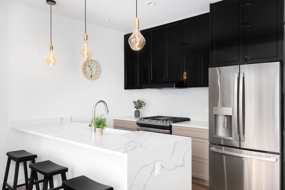 Modern kitchen with black cabinetry and a white quartz waterfall countertop.
