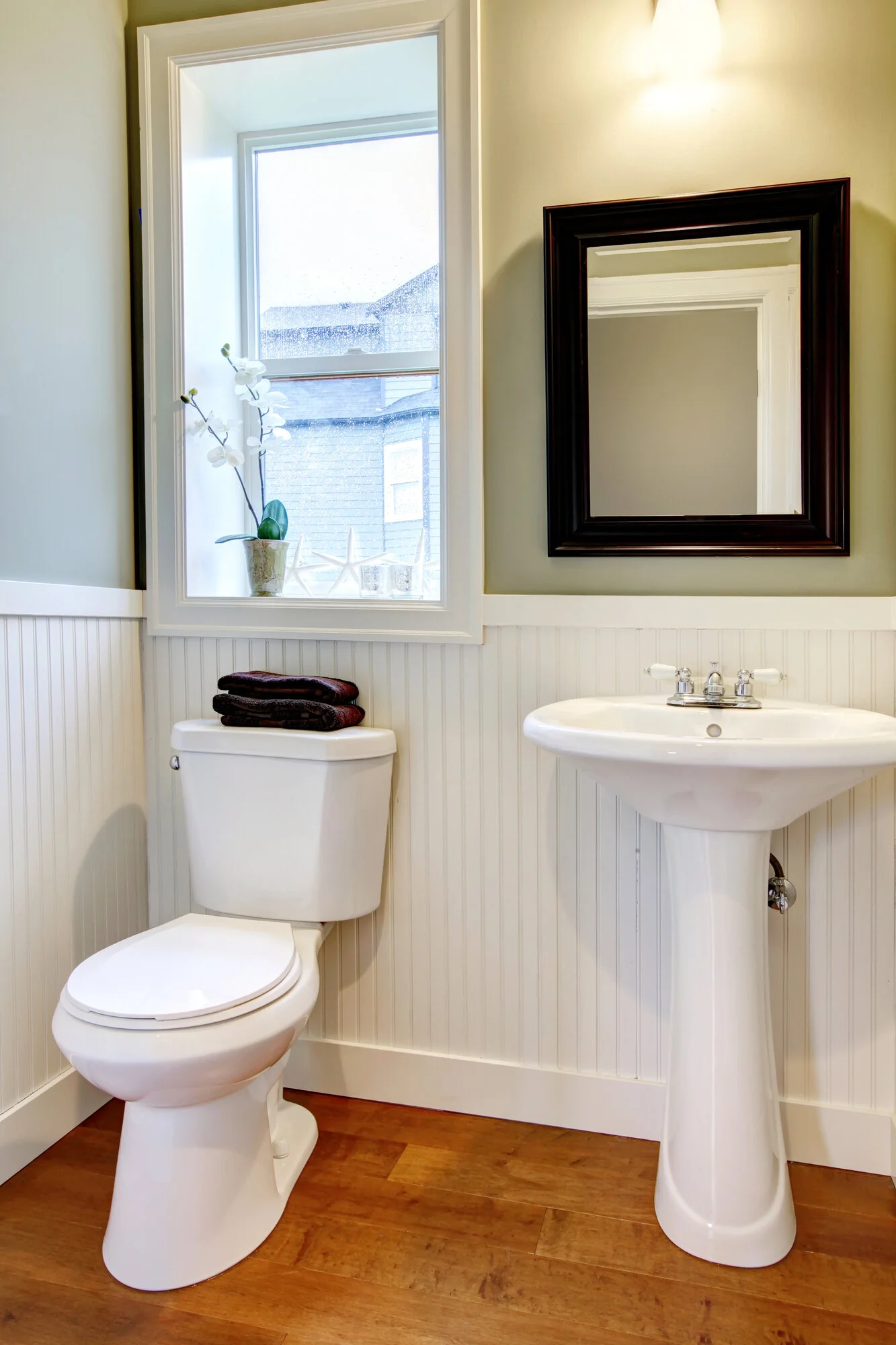 Small powder room with a pedestal sink, toilet, beadboard walls, and compact space-saving layout