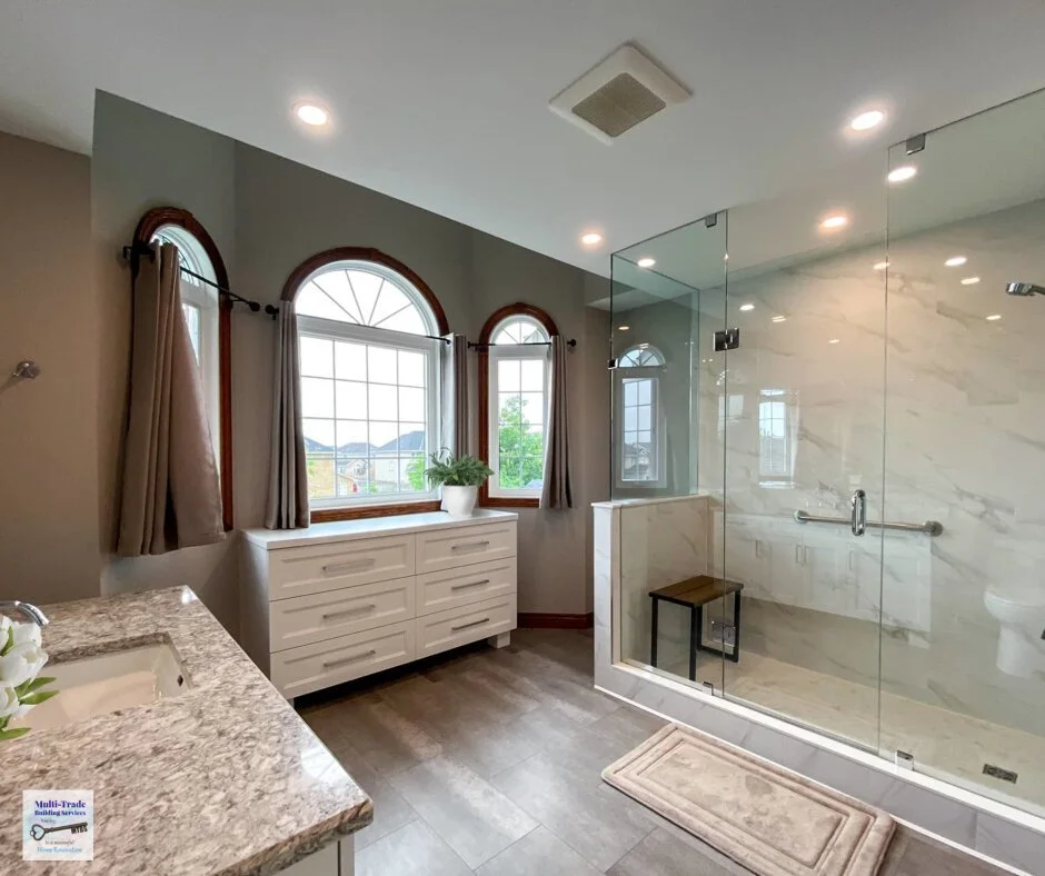 Spacious renovated bathroom with a large glass-enclosed walk-in shower, built-in bench and grab bars.