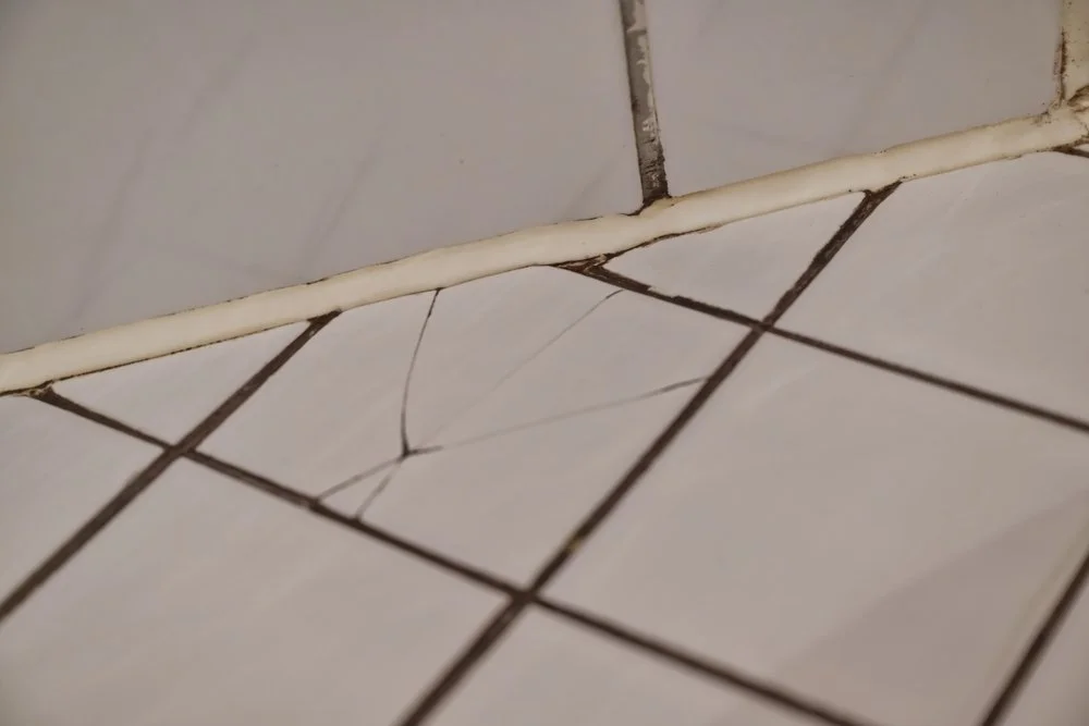 Cracked shower tile and deteriorating caulking allowing moisture behind shower walls