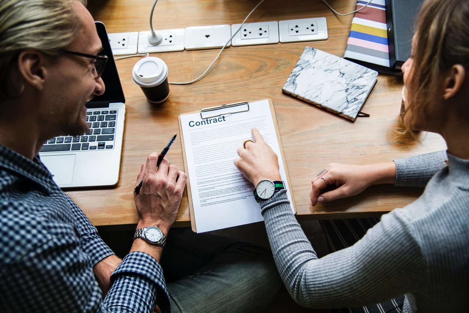 Homeowner reviewing a renovation contract with a contractor before signing, emphasizing the importance of understanding project scope, payment terms, warranties, and responsibilities.