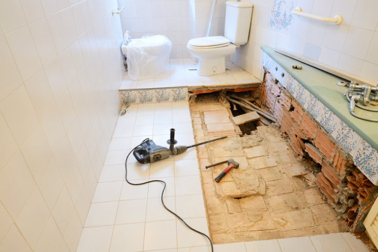 Bathroom renovation during demolition with sections of tile and flooring removed to expose the area underneath.