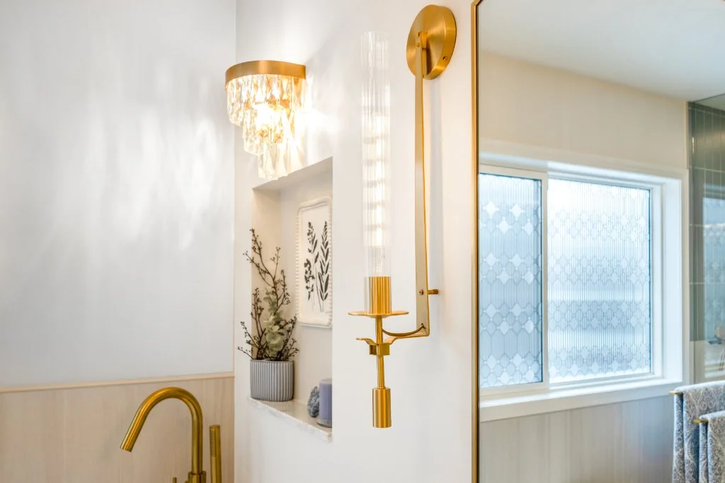 Designer gold wall sconce and custom recessed niche detail in a luxury ensuite bathroom renovation.