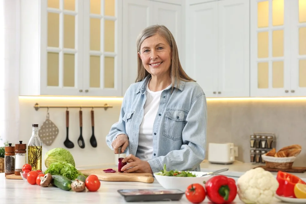 Homeowner preparing fresh vegetables in a bright, modern kitchen, illustrating how thoughtful kitchen design supports everyday cooking and functionality.
