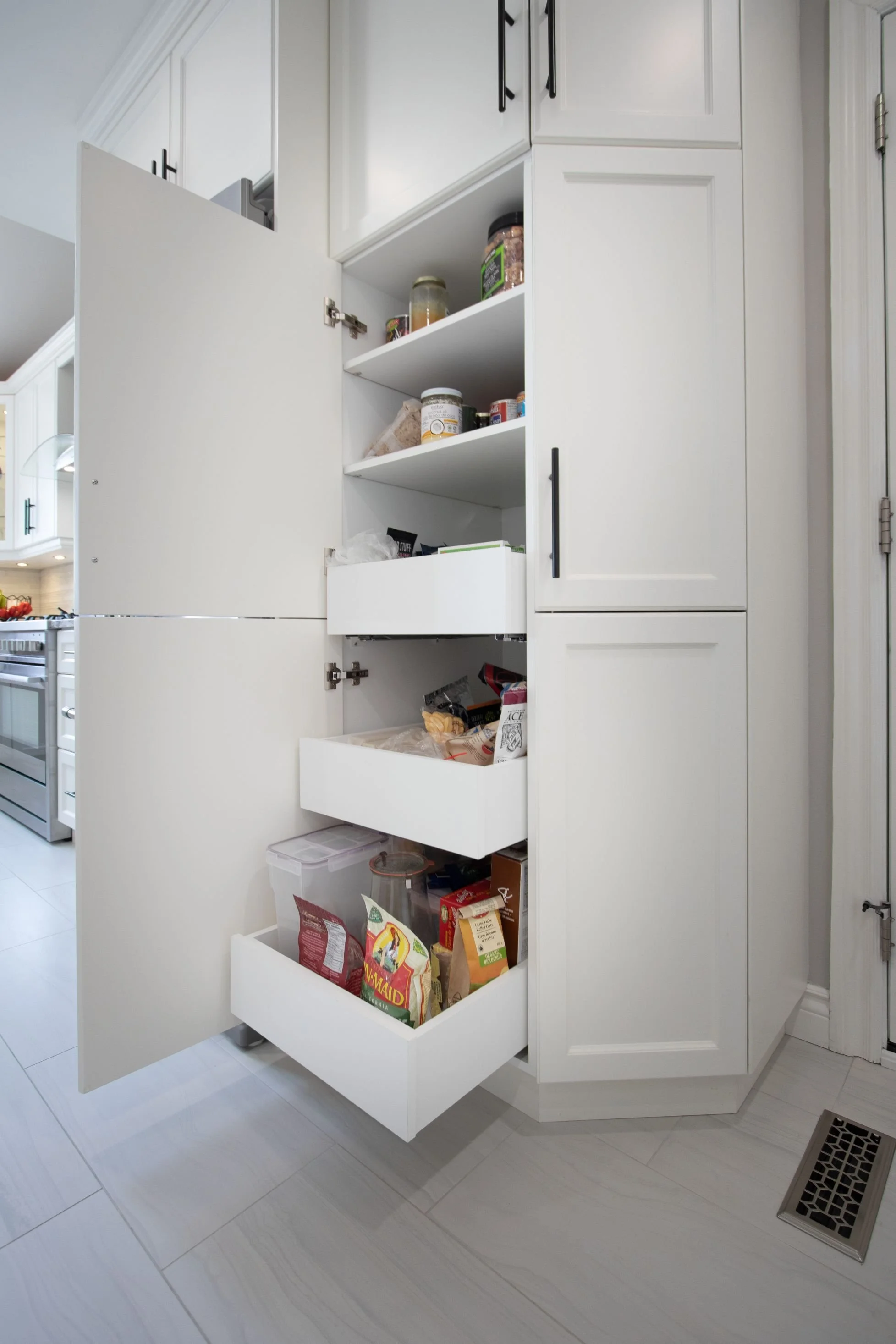 Tall kitchen pantry cabinet with lower pull-out drawers and upper adjustable shelves for organized storage.
