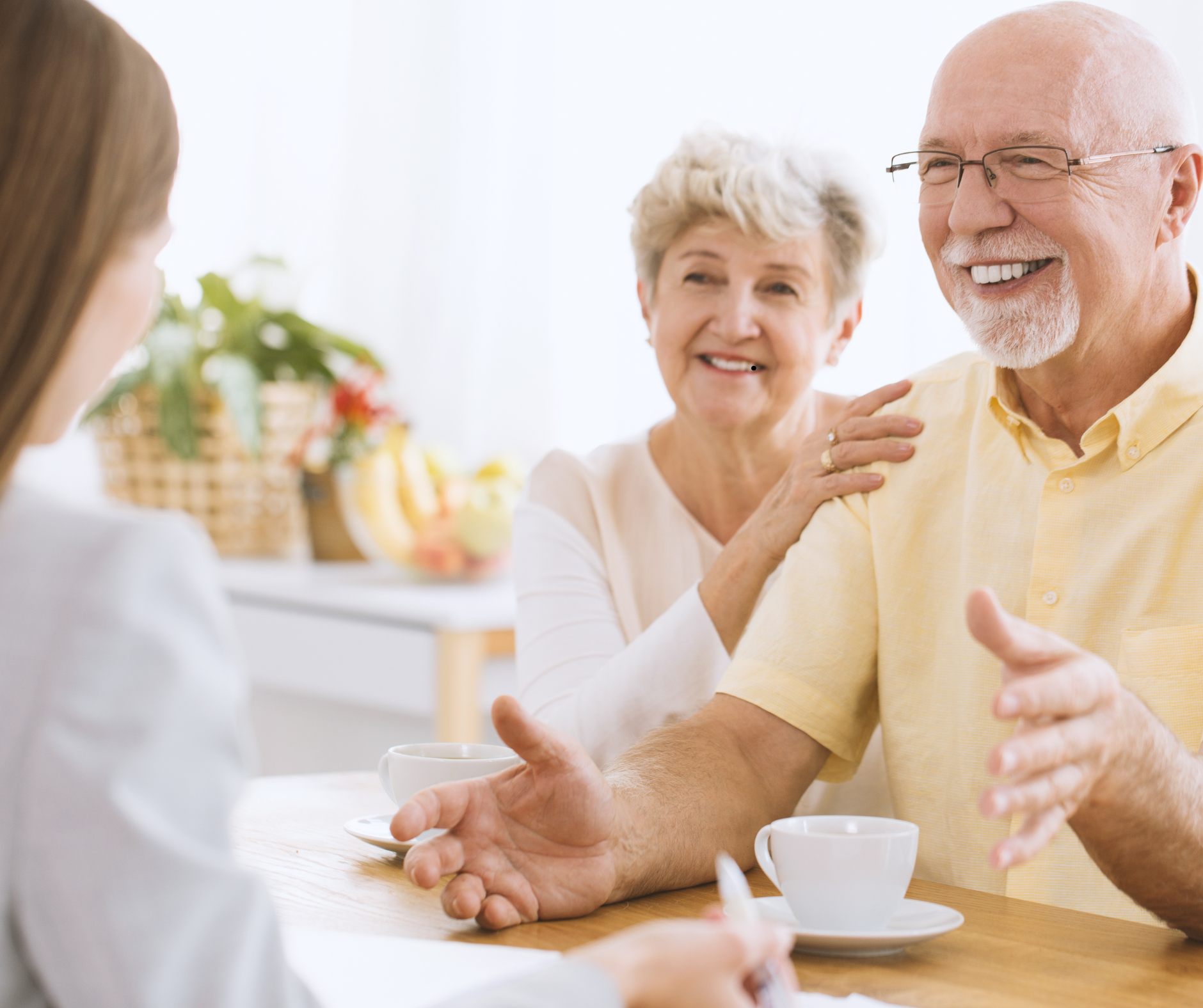Senior homeowners smiling and discussing renovation plans with their contractor in a relaxed, friendly meeting.