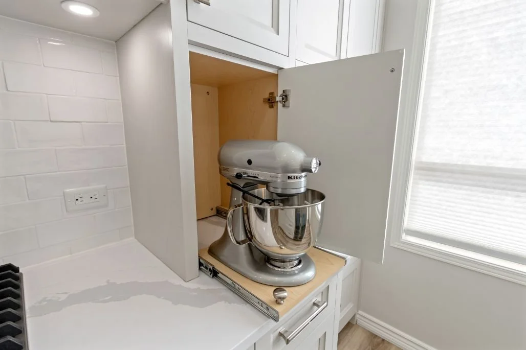 Kitchen appliance garage with pull-out shelf storing a stand mixer for easy access and clutter-free countertops.