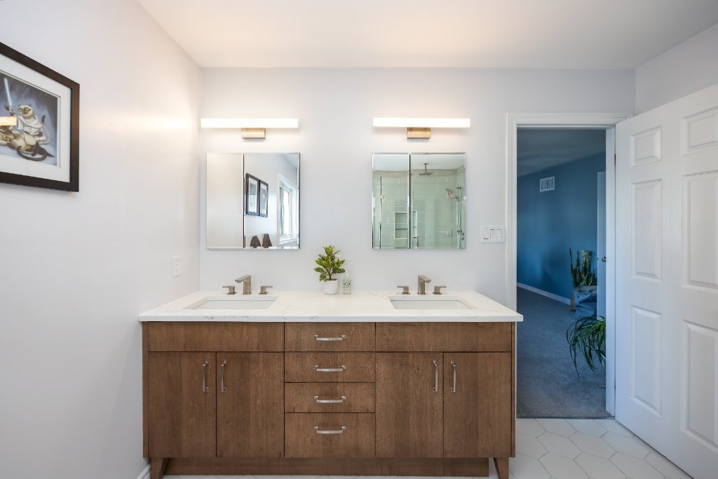 Wood double sink vanity with white countertop, undermount sinks, separate mirrors and centre drawer storage.