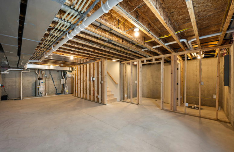 Unfinished basement renovation with exposed framing, plumbing, ductwork and electrical rough-ins before drywall and finishing.