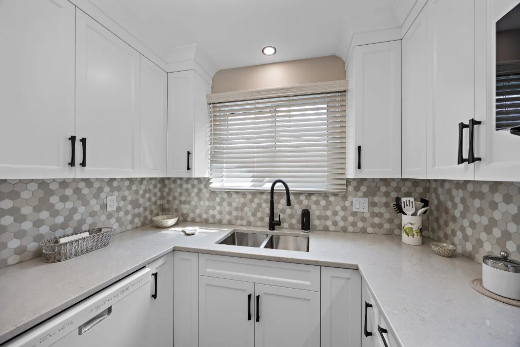 Modern white kitchen renovation with hexagon tile backsplash, quartz countertops and double sink design for improved workflow