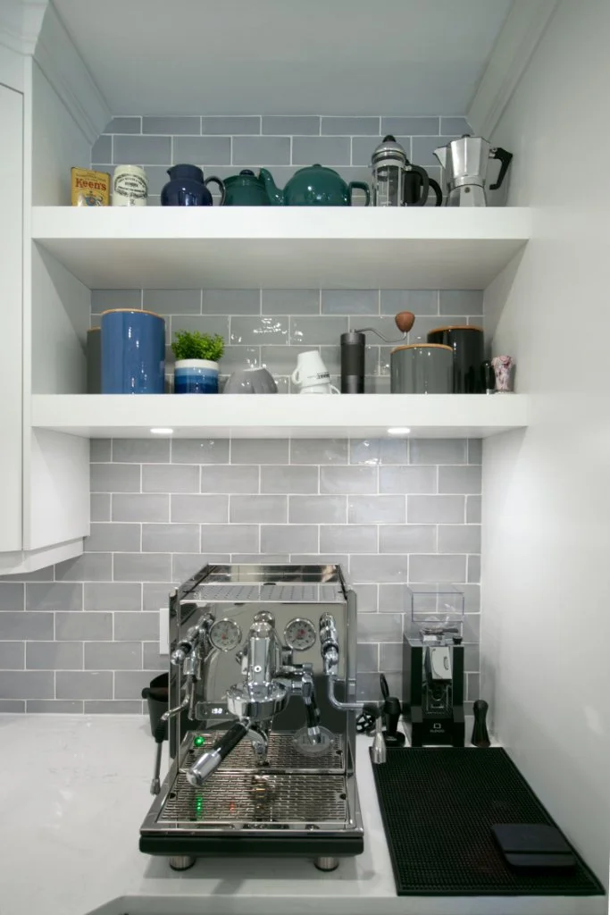 Built-in coffee nook with open shelves, gray subway tile backsplash and an espresso machine.
