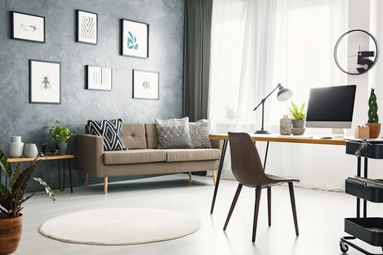 Home office incorporated into a multipurpose living space with a desk, computer, sofa and natural light.