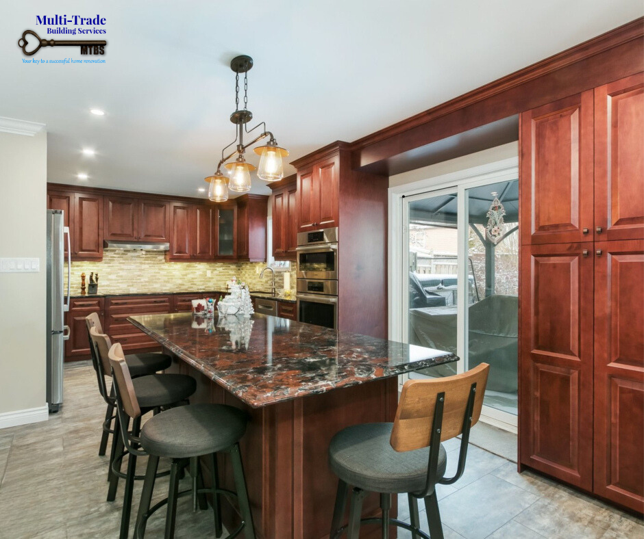 Large kitchen island with granite countertop, seating, pendant lights and warm wood cabinetry.