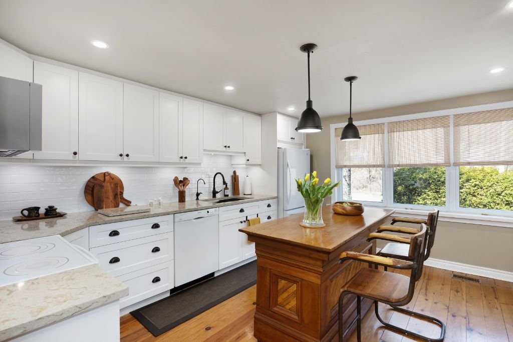 L-shaped kitchen with a central island, open sightlines, and accessible workspace designed for empty nesters and aging in place.