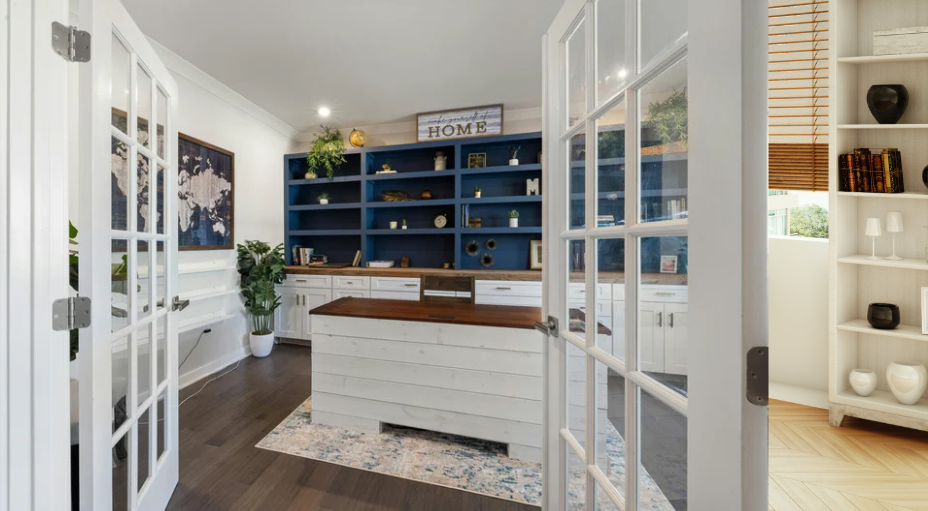 Dedicated home office with built-in shelving, cabinetry, a large work surface and French doors.