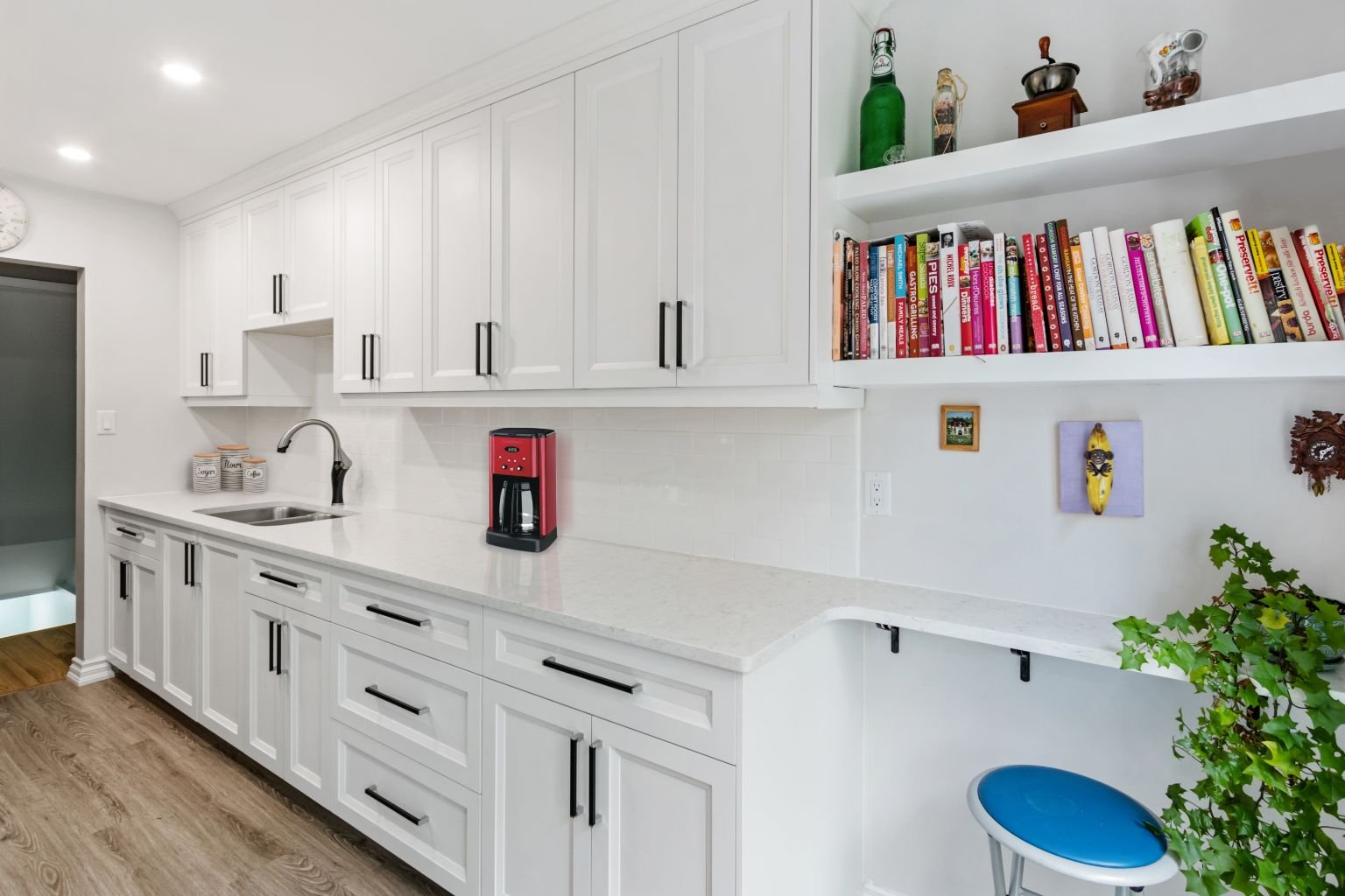 Custom kitchen renovation featuring extended quartz countertop, white cabinetry and integrated storage solutions for improved functionality