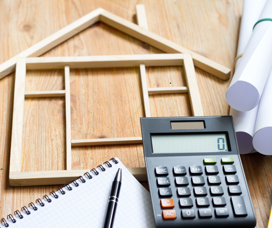 Model house frame, calculator, and renovation planning tools on a wooden surface—symbolizing budgeting and preparation for home renovations.
