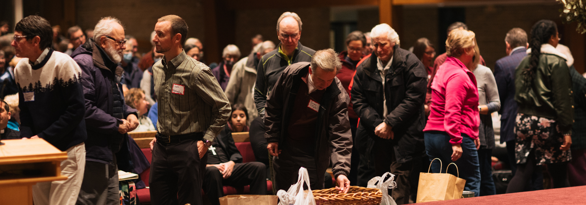 Attendees bringing offerings of food and money to contribute to local food pantries.