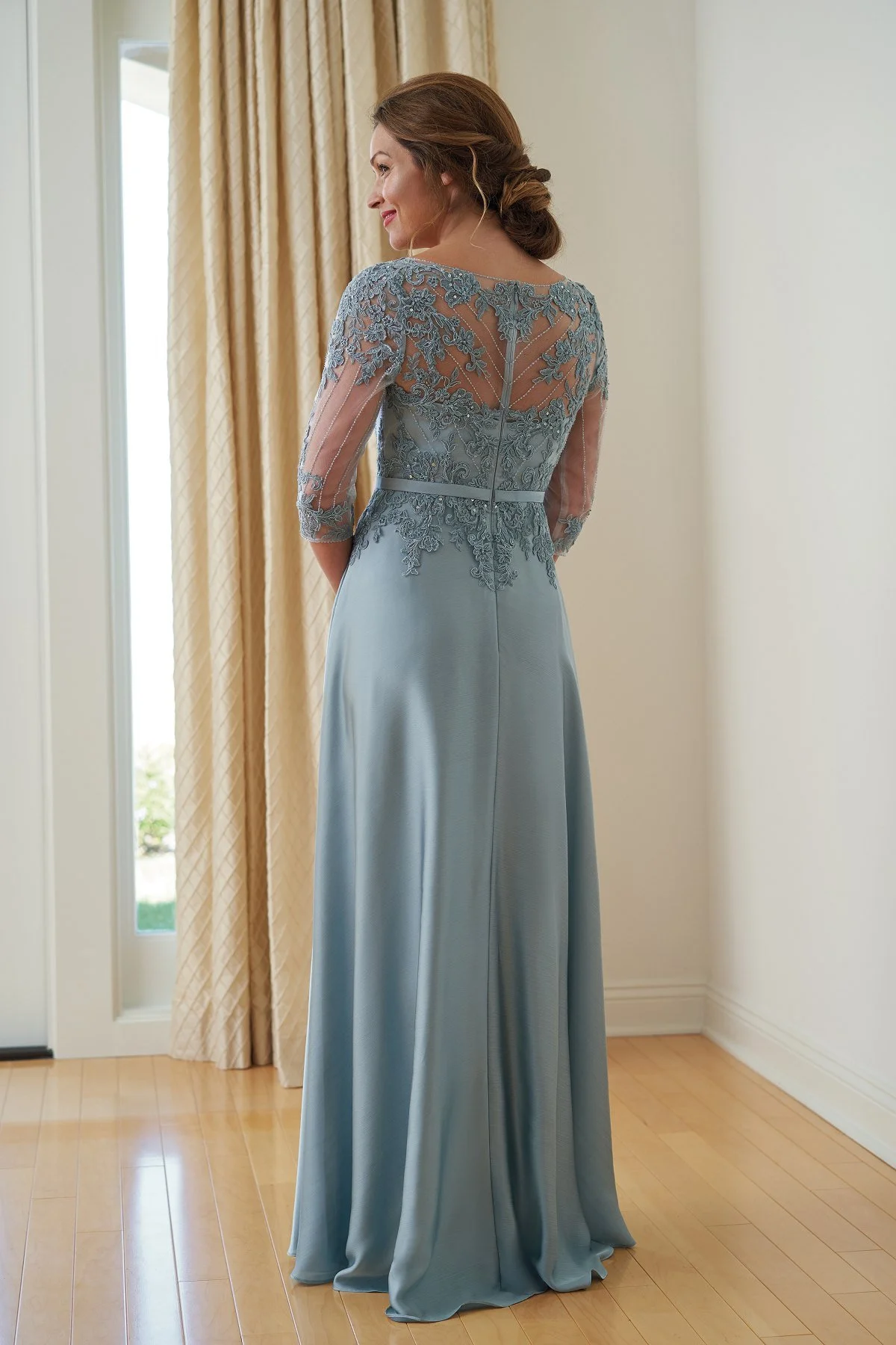 Back view of an ice blue mother of the bride gown with an illusion lace back, embroidered three-quarter sleeves, intricate lace appliqué, and a flowing A-line skirt for weddings and formal occasions.