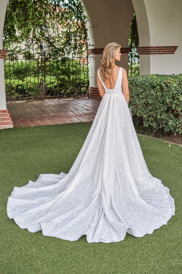 Back view of a jacquard A-line wedding dress featuring a low V-back, wide shoulder straps, textured floral fabric, and a dramatic sweeping train for a timeless and elegant bridal look.