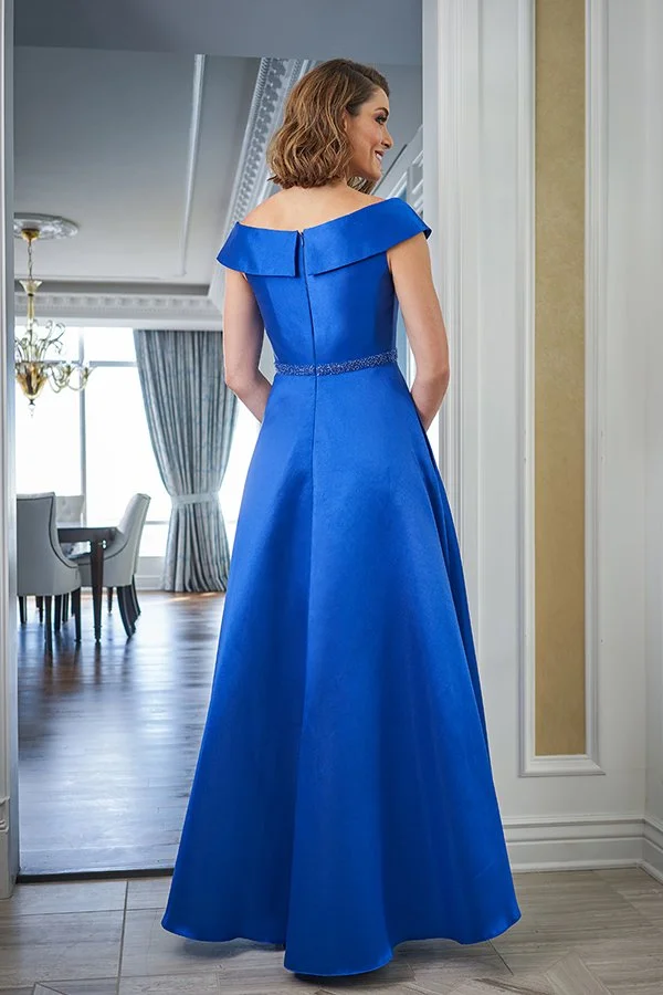 Back view of a royal blue off-the-shoulder mother of the bride gown featuring an A-line silhouette, beaded waistband, and full satin skirt in a refined indoor setting.
