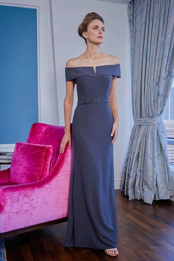 Front view of a slate blue mother of the bride gown with an off-the-shoulder neckline, subtle notch detail, sparkling beaded waistband, and a sleek floor-length column silhouette for formal weddings.