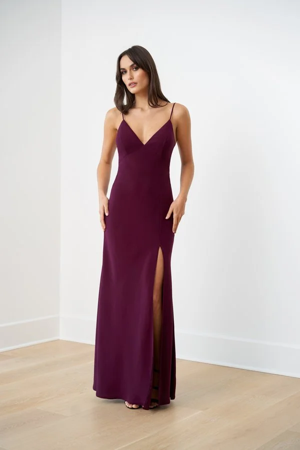 Woman modeling a berry bridesmaid dress featuring a V-neckline, delicate spaghetti straps, sleek column silhouette, and elegant front slit for formal occasions.