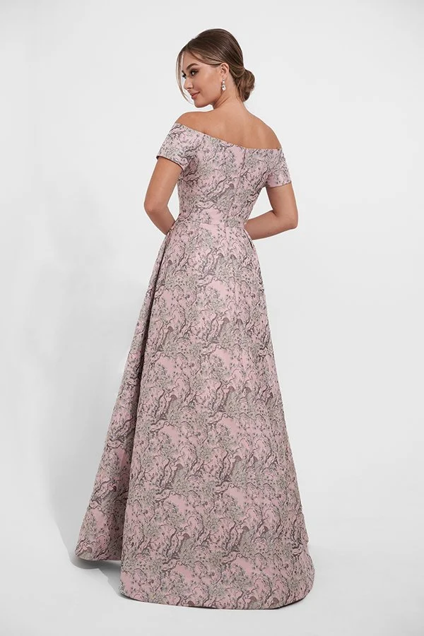 Back view of an elegant blush mother of the bride gown with an off-the-shoulder neckline, metallic jacquard fabric, fitted bodice, and a full A-line silhouette for weddings and formal occasions.