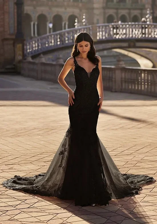 Bride models a dramatic black lace mermaid wedding dress with a deep V-neckline and cathedral train, showcasing alternative bridal fashion, elegant gothic-inspired wedding style, and timeless bridal portrait photography.