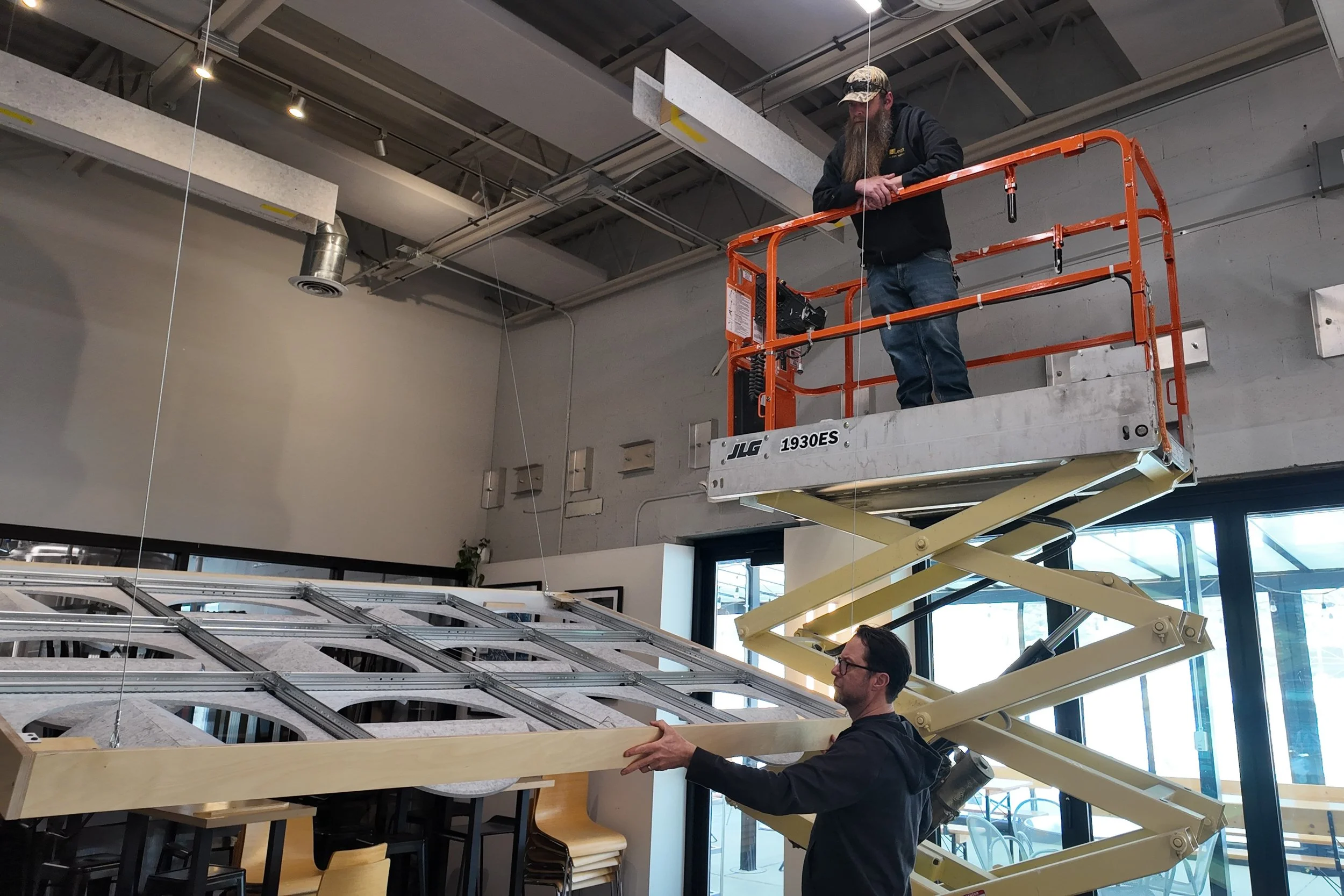 Two men installing the Leon x Askia Acoustic Island inside the Mothfire Taproom