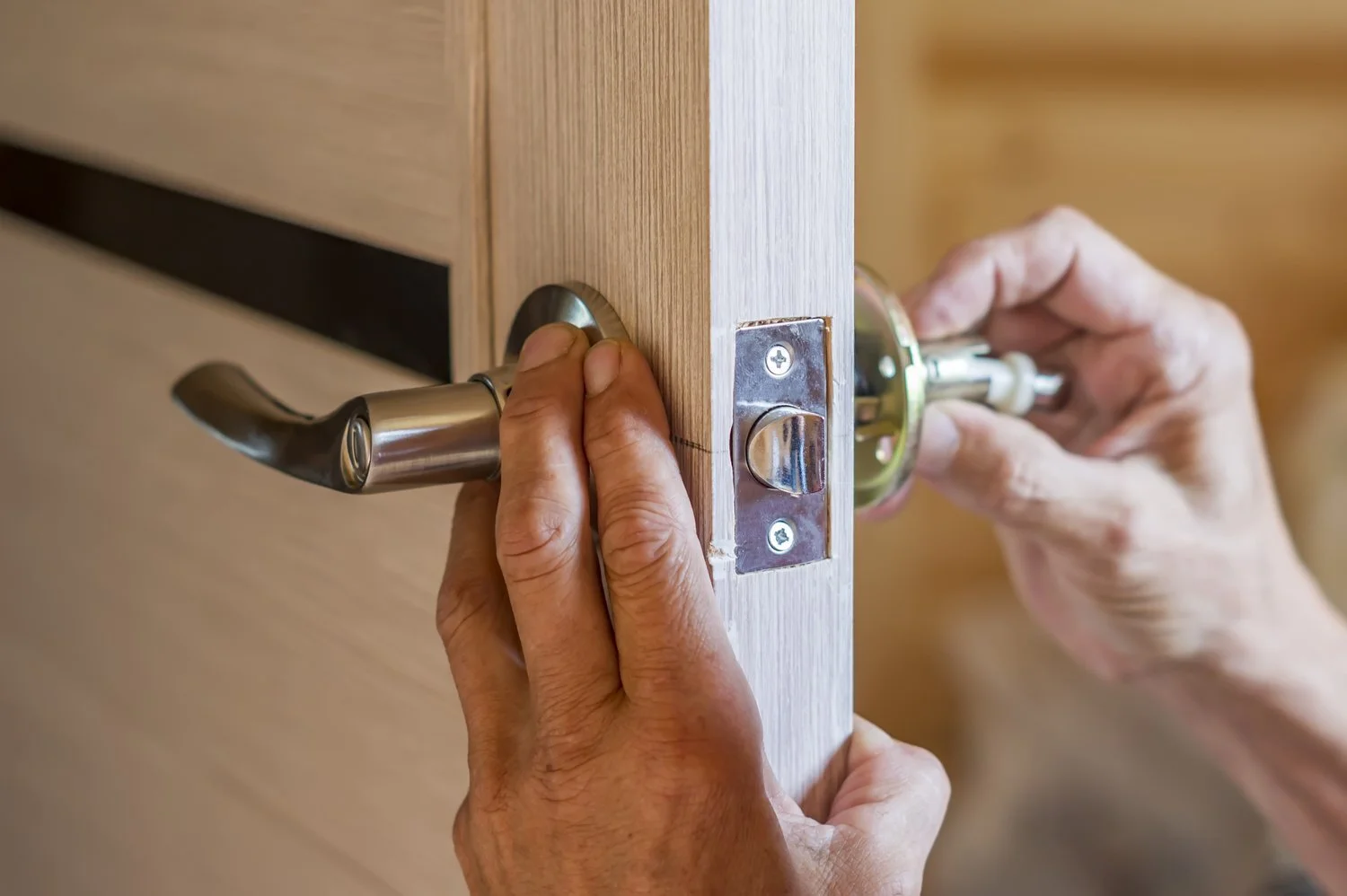 Person installing a new door lock as part of basic new homeowner safety tasks.