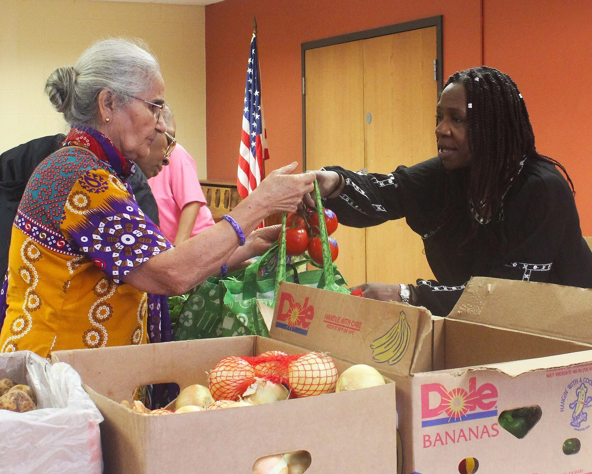 A volunteer handing produce to a client at a High Rise Mobile Food Shelf.