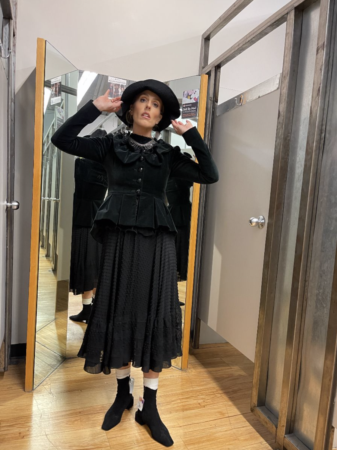Black velvet jacket, long skirt and hat tried on in a thrift shop fitting room