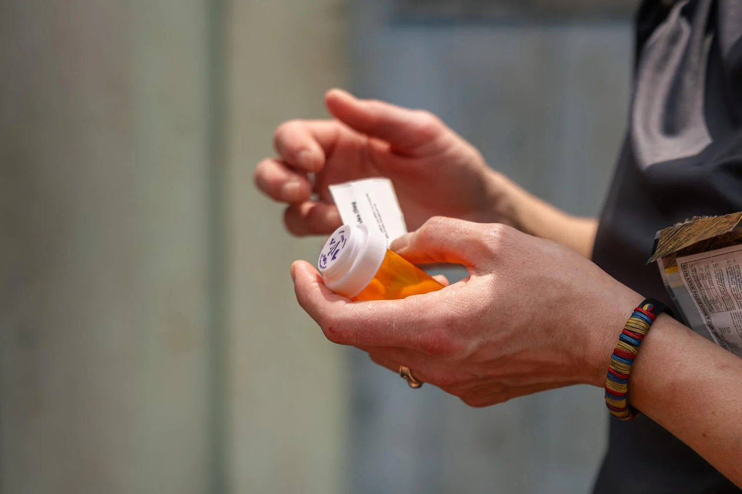Close-up of a veterinary team member’s hands holding a small bottle of medication during a community vet visit in the Amazon.