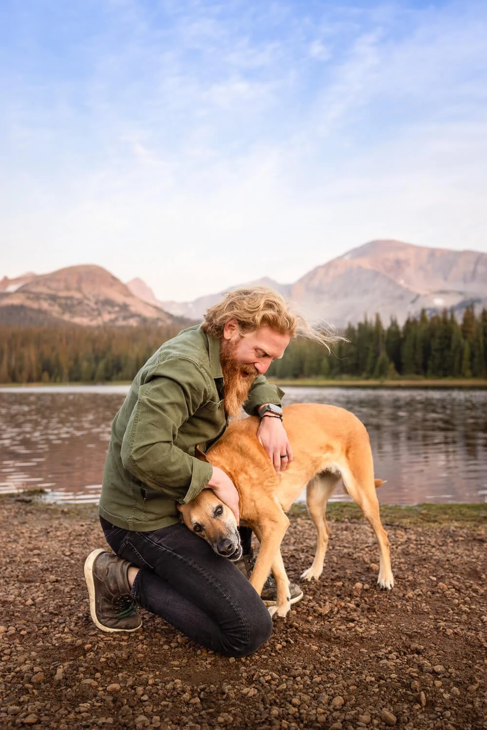 A man and his dog sharing a candid, connected moment during a sunset photography session in the Colorado mountains.