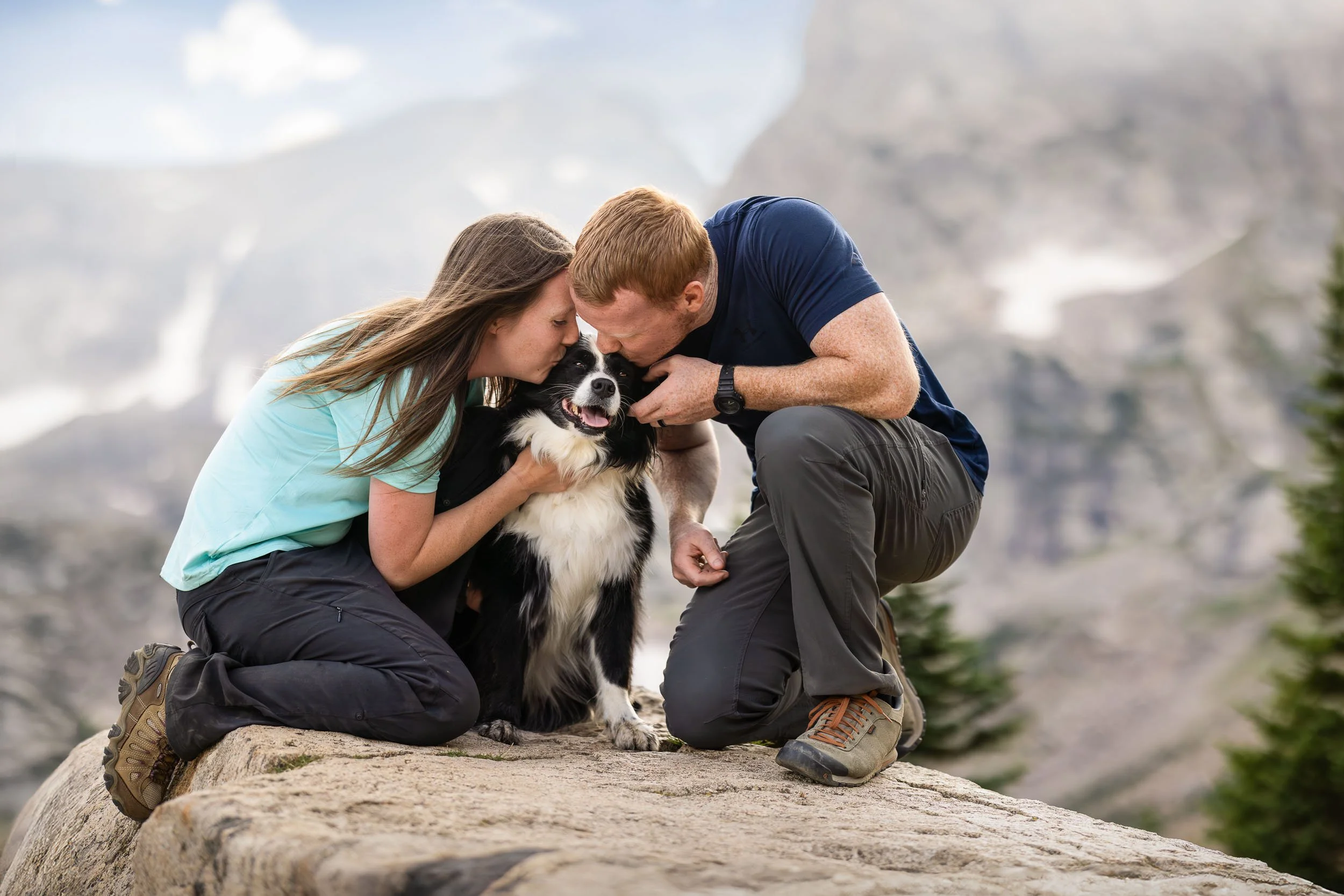 A couple snuggles their dog while taking a break from hiking in the Colorado Rockies.