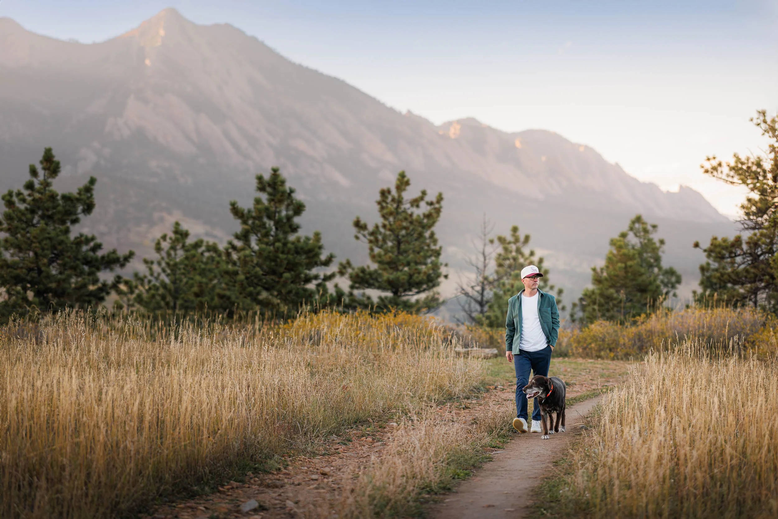 A dog walks with his owner on a trail in Boulder during a pet photography session.