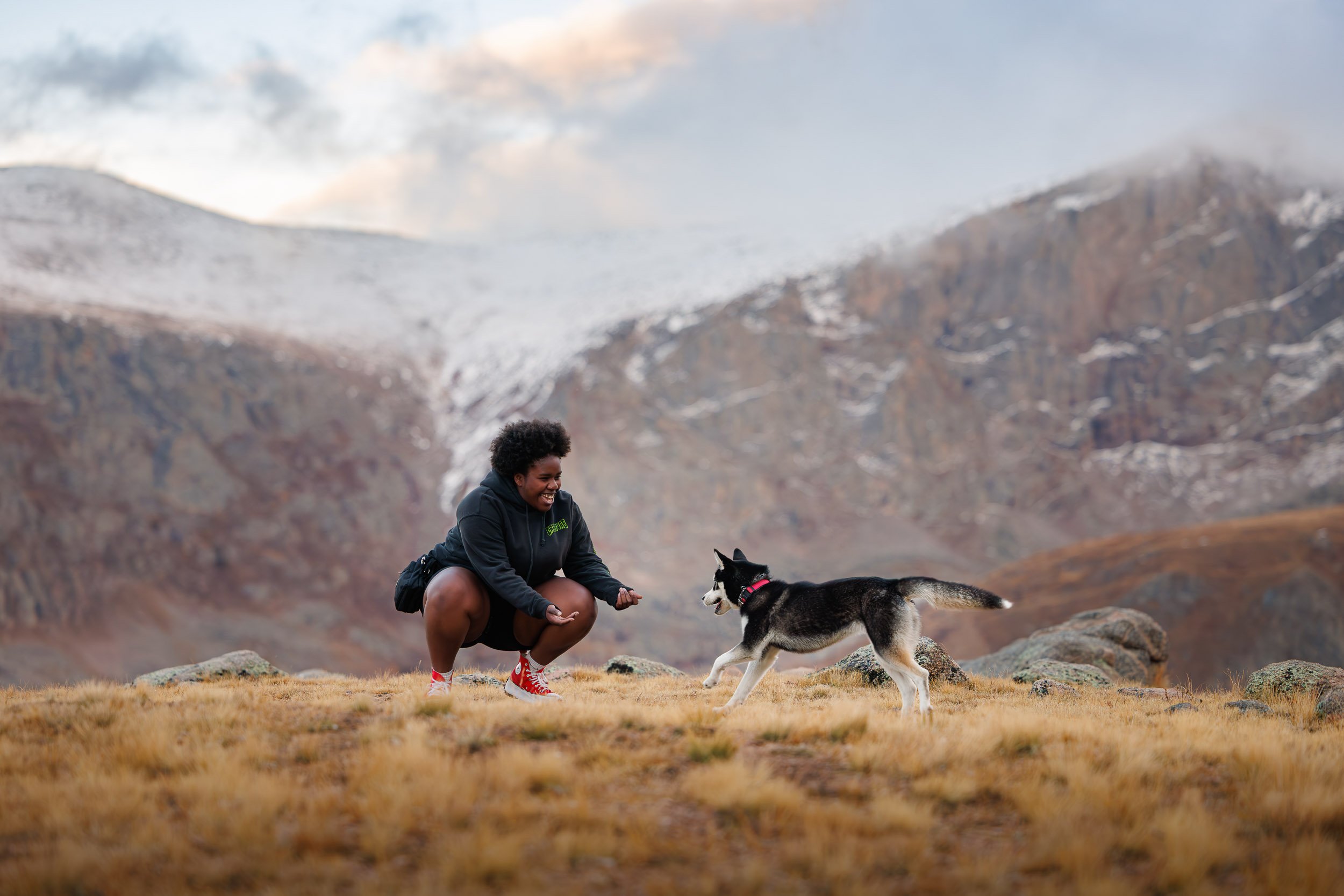 Dramatic sunset light hitting a dog trainer and their dog during a stormy mountain branding session in the Colorado Rockies.