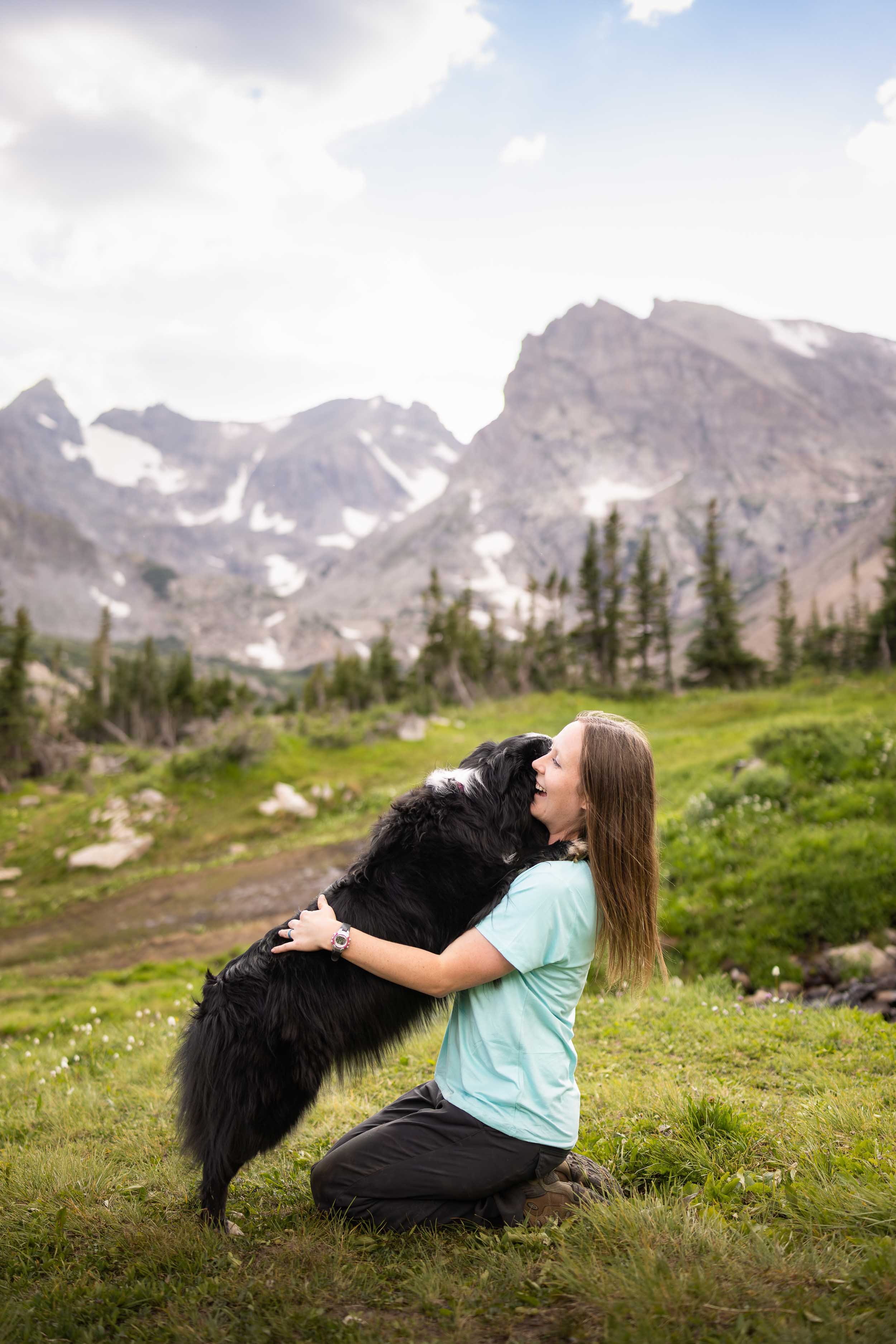 A happy dog gives her owner a hug on a trail.