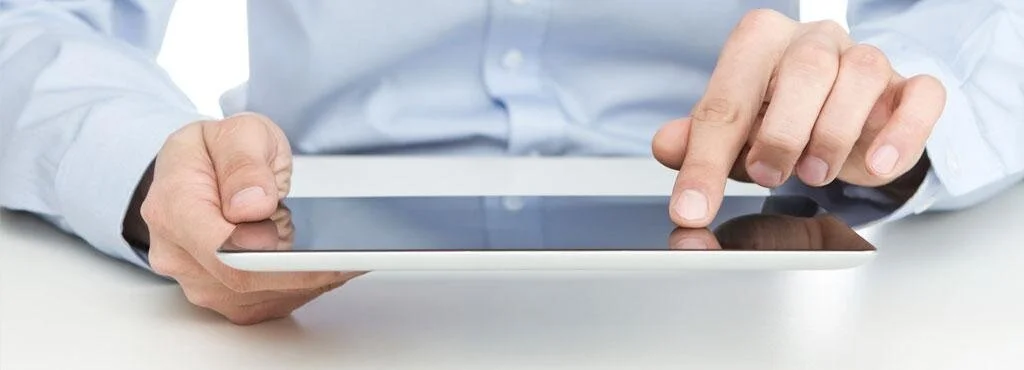 man-lightblue-shirt-sitting-table-scrolling-tablet.jpg