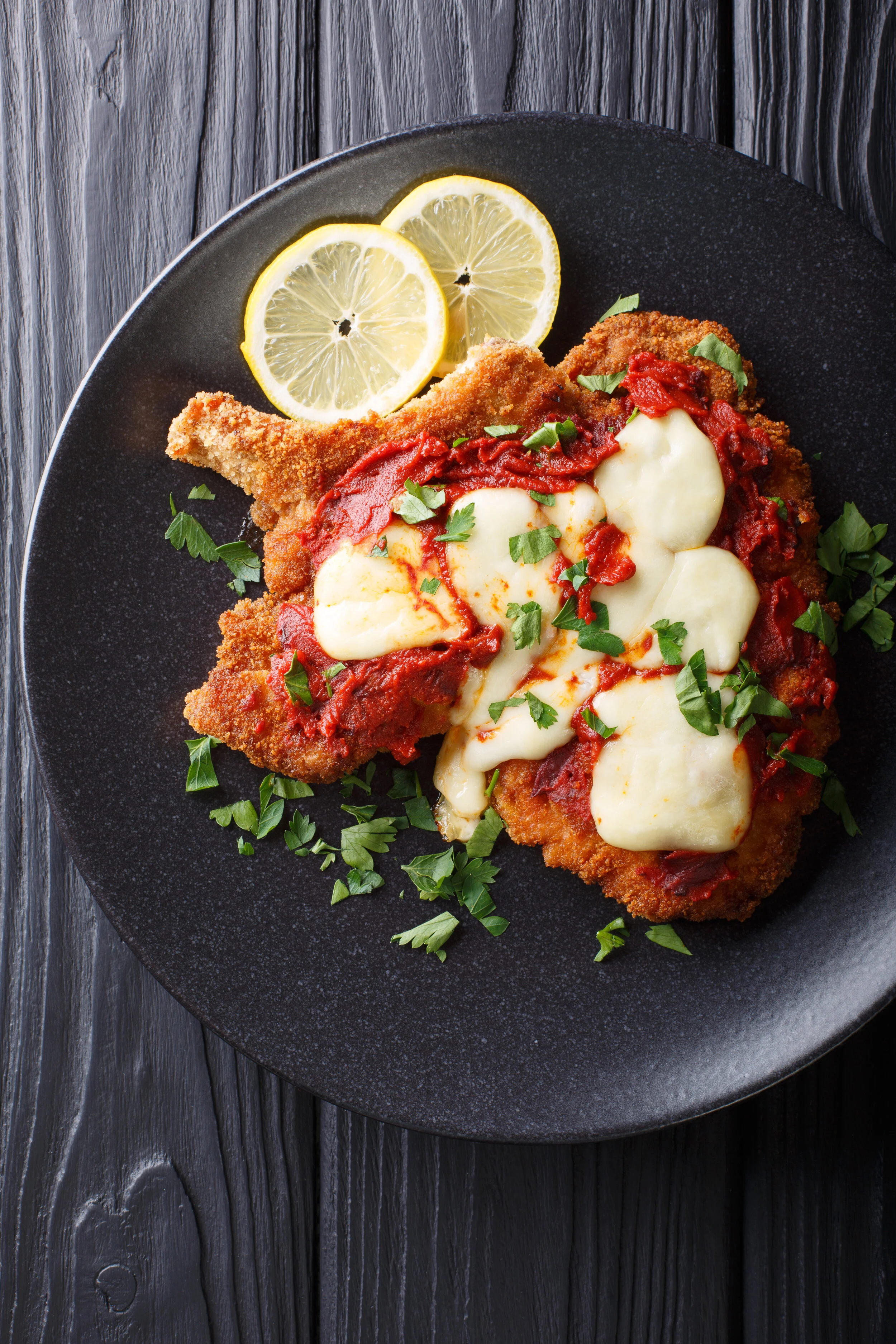 La milanesa-napolitana---homemade-veal-cutlet-with-mozzarella-cheese,-lemon-and-tomato-sauce-close-up.-Vertical-top-view-1057833346_3840x5760.jpeg
