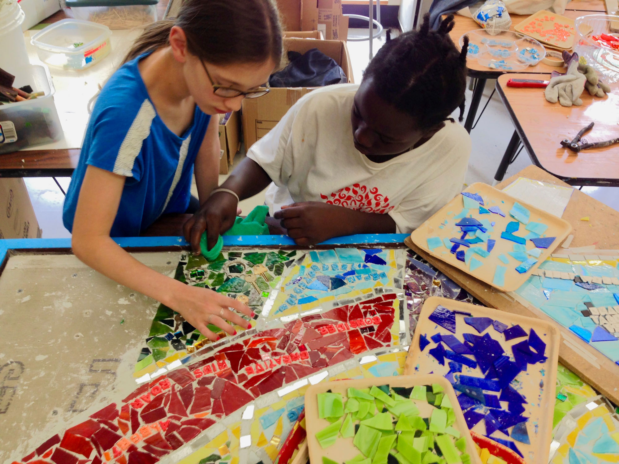 Adhering the mosaic pieces to the sign backing.