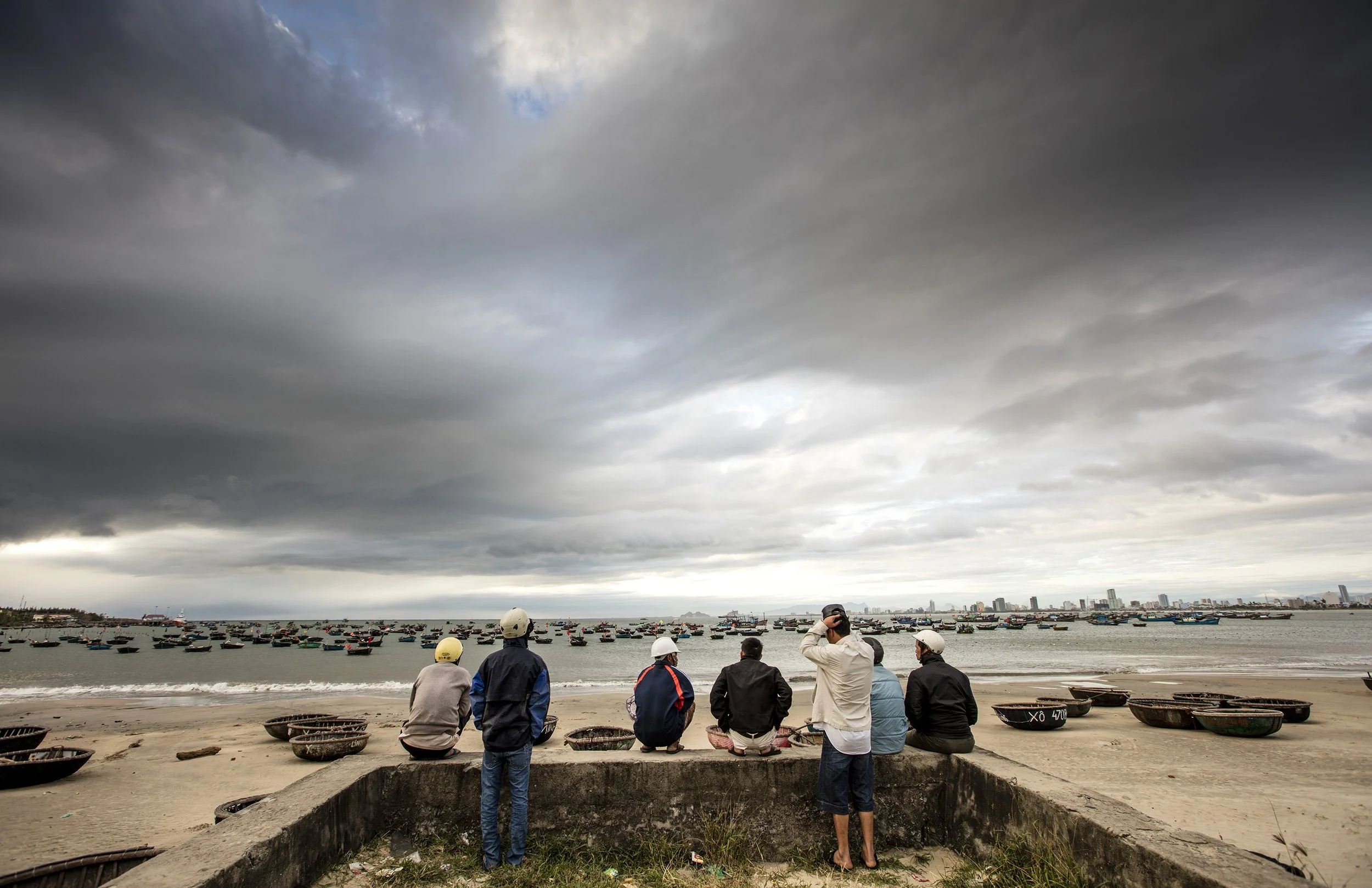 men sit on the beaches of Danang in Vietnam