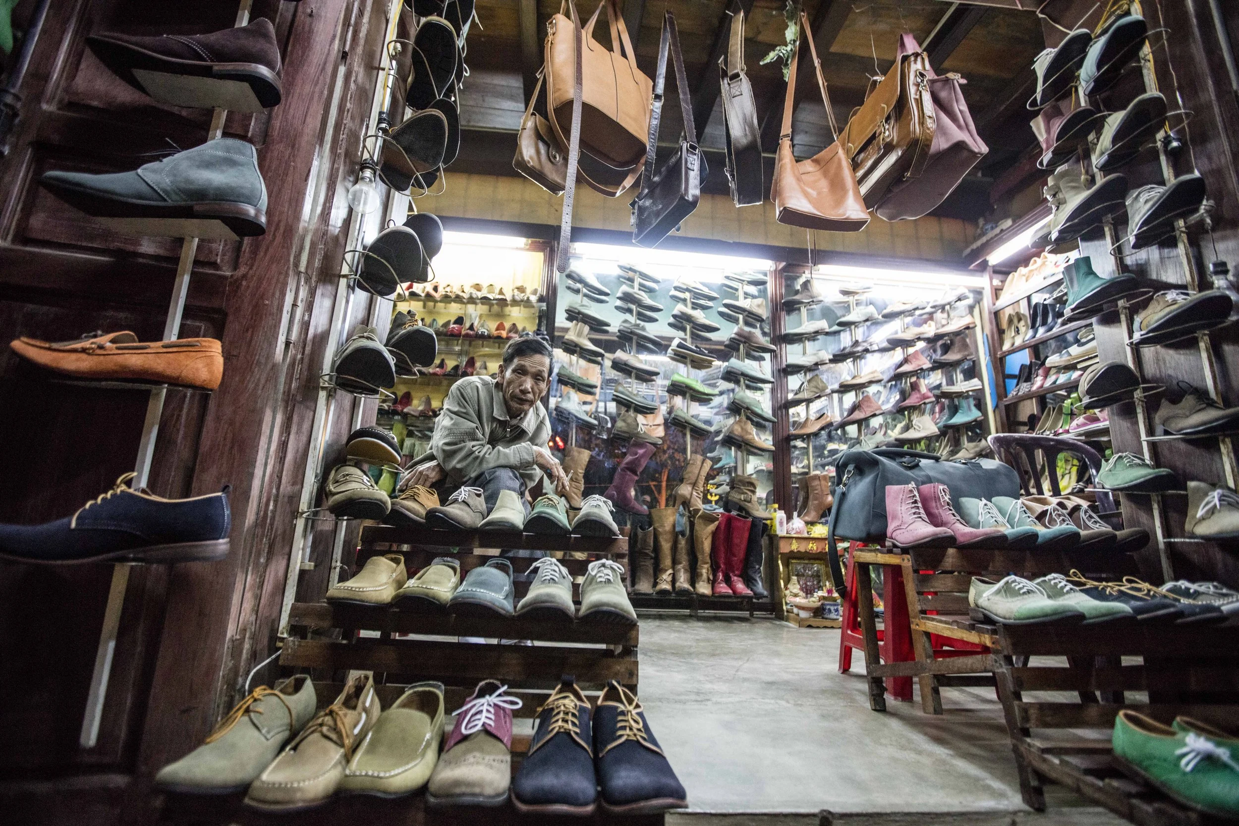 a man sits outside his show shop in vietnam