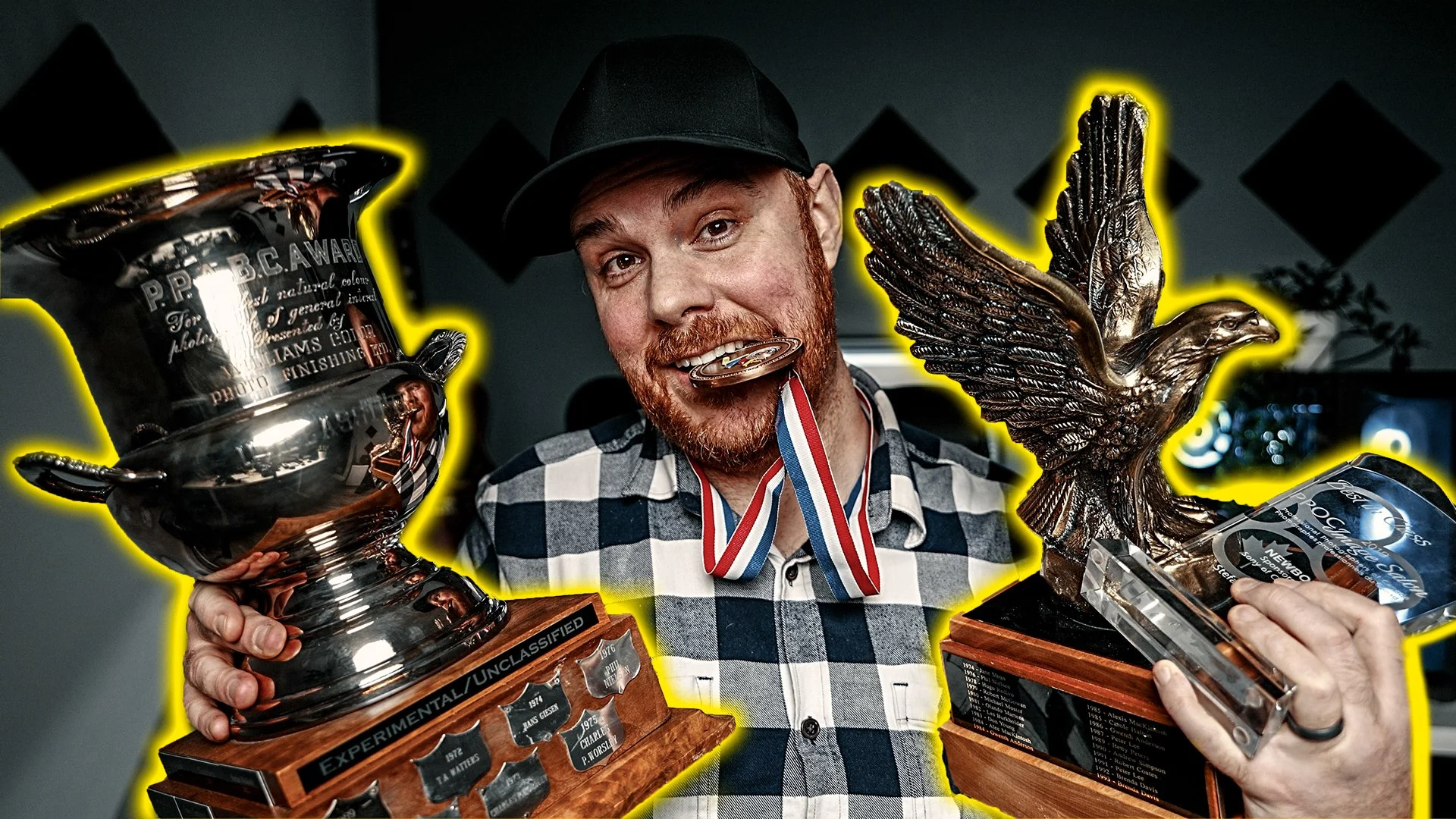 Stefan Malloch holding his photography trophies, award plaque and medal.