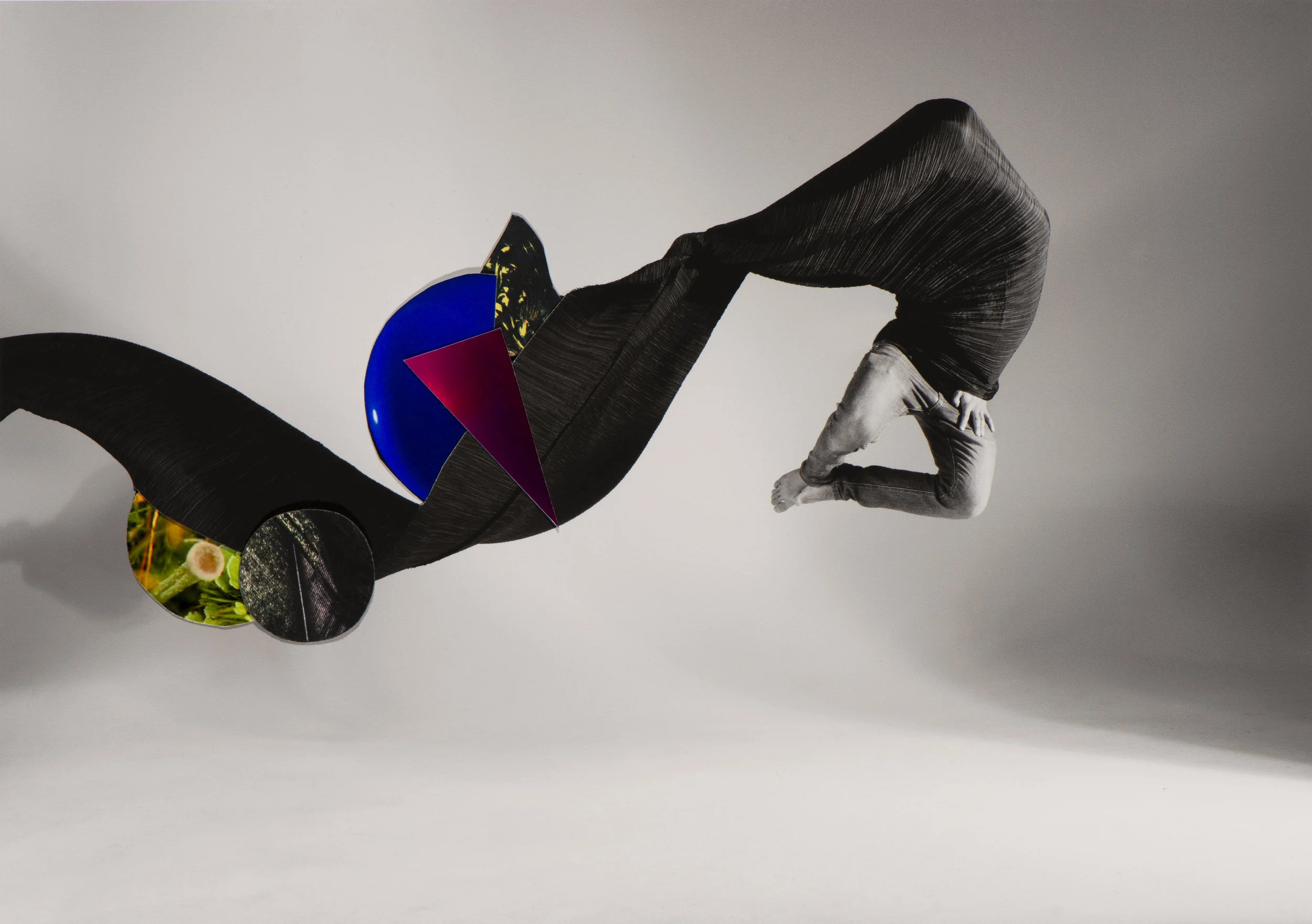 Abstract art installation with a person in a curled position, surrounded by geometric shapes and patterns, on a plain background.